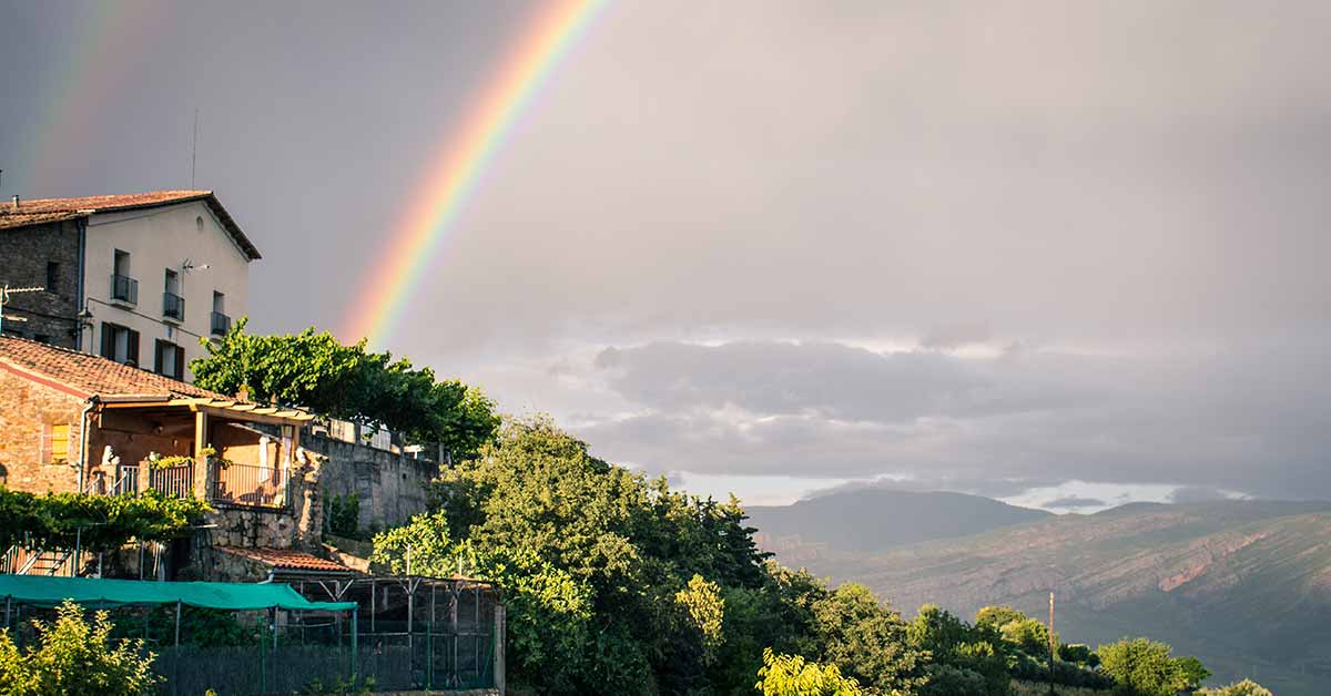 Double rainbow shines over a house during a storm