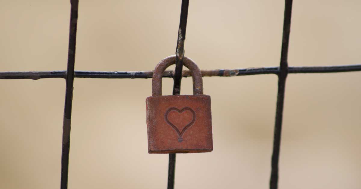Close up view of a rusty lock with a heart engraved into the front